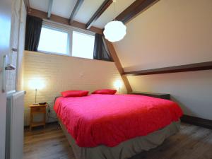 - une chambre dotée d'un grand lit avec des draps rouges et d'une fenêtre dans l'établissement Cosy Holiday Home in Limburg with Forest nearby, à Stramproy