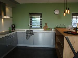 a kitchen with green walls and white cabinets at These two holiday homes built in 2006 in Zuidzande