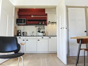 a kitchen with white cabinets and a black chair at Fisherman s house near the Lauwersmeer in Zoutkamp