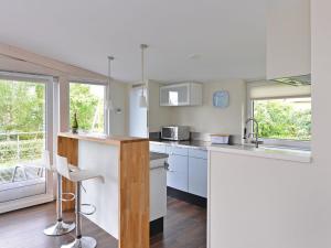 a kitchen with white counters and white cabinets and windows at Holiday Home in Kamperland by Veerse Meer in Kamperland