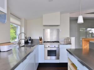 a kitchen with white cabinets and a stove top oven at Holiday Home in Kamperland by Veerse Meer in Kamperland +32 photos