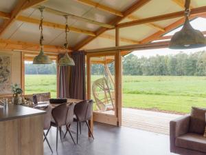 a living room with a table and chairs and a large window at Special tent lodge with dishwasher, in Twente in Buurse