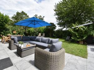 un canapé bleu et des chaises avec un parapluie bleu dans l'établissement Holiday home in Zeeland with wide views, à Bruinisse