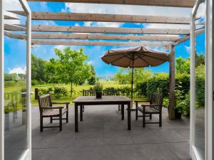 un patio con mesa, sillas y sombrilla en Pretty Holiday Home in Vroomshoop with Garden, en Vroomshoop