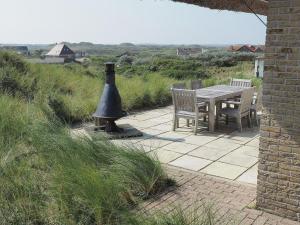 a table and chairs on a patio with a bird bath at Beautiful villa on Terschelling in the dunes 150 meters away in Midsland aan Zee