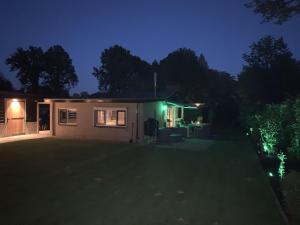 uma casa iluminada à noite com luzes verdes em Holiday home with covered porch and sauna em Voorthuizen