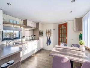 a kitchen with a wooden table and purple chairs at Chalet Sea Rocks with view and garden in Goedereede