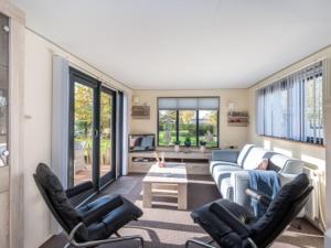 a living room with a couch and chairs and a table at Chalet Sea Rocks with view and garden in Goedereede