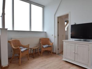 een woonkamer met 2 stoelen en een flatscreen-tv bij Apartment with stunning views in Bergen aan Zee