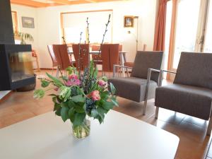 um vaso de flores sobre uma mesa com cadeiras em Relax in a luxury villa by the dunes em De Cocksdorp