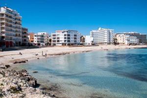 een strand met gebouwen op de achtergrond van een stad bij aptsmile sillot in S'Illot