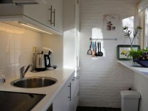een witte keuken met een wastafel en een aanrecht bij Modern bungalow in South Holland in Noordwijkerhout