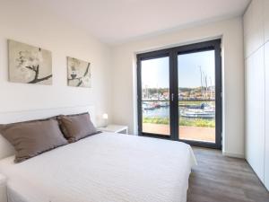 ein weißes Schlafzimmer mit einem großen Bett und einem großen Fenster in der Unterkunft New and tasteful apartment with a panoramic view over the marina in Kamperland