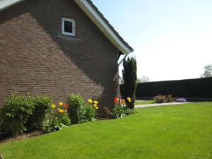 uma casa de tijolos com um quintal com flores em Tranquil Holiday Home in Margraten with Terrace and Garden em Margraten