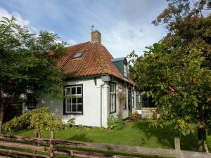 uma casa branca com um telhado vermelho em Fairytale Cottage in Nes Friesland with garden em Nes