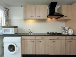a kitchen with a washing machine and a microwave at Fairytale Cottage in Nes Friesland with garden in Nes