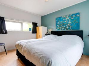 1 dormitorio con 1 cama blanca grande y pared azul en Lovely Chalet near the Lauwersmeer Lake, en Anjum