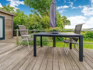 una mesa negra y sillas en una terraza con sombrilla en Lovely Chalet near the Lauwersmeer Lake, en Anjum