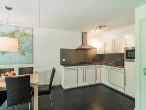 una cocina con armarios blancos y una mesa con comedor. en Comfortably vacation home at Slotermeer Lake, en Balk