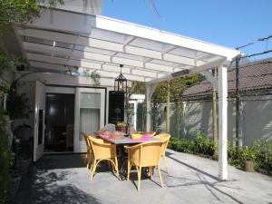 une terrasse avec une table et des chaises sous une pergola blanche. dans l'établissement Welcoming Holiday Home in Heiloo with Sunlit Terrace, à Heiloo