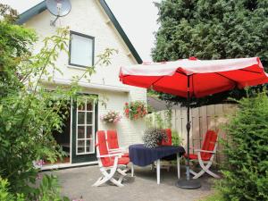 スコールルにあるDetached holiday home in the centre of the forest in Schoorlの家の前にテーブルと椅子と傘