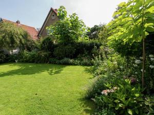 a garden with green grass and trees and a house at Apartment in Bergen near Schoorl Dunes in Bergen