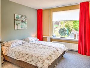 スコールルにあるModern Apartment in Schoorl near the Beachのベッドルーム1室(ベッド1台付)、赤いカーテン付きの窓が備わります。