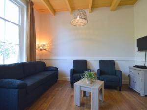 een woonkamer met een bank, 2 stoelen en een tafel bij Alluring Holiday Home in Geesteren with Terrace in Geesteren