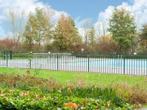une clôture noire dans un parc avec un étang dans l'établissement Captivating Holiday Home in Zeewolde near Forest, à Zeewolde