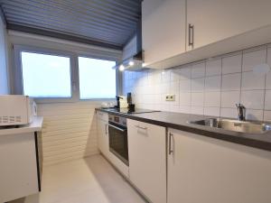 ベルゲン・アーン・ゼーにあるUnique holiday home in Bergen aan Zee with terraceの白いキャビネットとシンク付きのキッチン、窓2つが備わります。