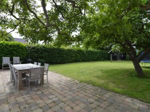 een tafel en stoelen op een stenen patio met een boom bij Nice holiday home on the Dutch coast with terrace in Nieuwvliet