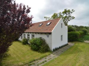 een klein wit huis met een rood dak bij Nice holiday home on the Dutch coast with terrace in Nieuwvliet