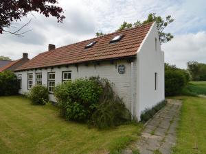 een oud wit huis met een rood dak bij Nice holiday home on the Dutch coast with terrace in Nieuwvliet