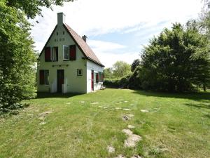 アウウドルプにあるQuintessential holiday home in Ouddorp with gardenの赤窓と庭のある白い家