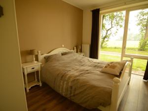 1 dormitorio con cama blanca y ventana en Rural holiday home with a lovely sunny terrace, en Workum