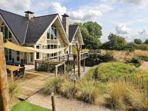 een huis met een houten terras en een schommel bij Luxurious Holiday Home with bubble bath in Noordwijk in Noordwijk