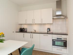a kitchen with white cabinets and a table at Apartment in Zoutelande near the Beach in Zoutelande