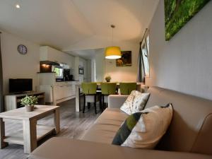een woonkamer met een bank en een tafel bij Nice chalet with dishwasher and wooded location in Vorden
