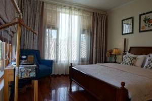 a bedroom with a bed and a blue chair and a window at Dali Yunxi Boutique Inn in Dali