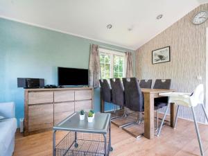 uma sala de estar com uma mesa e cadeiras e uma televisão em Charming Chalet in Stegeren near Forest em Stegeren
