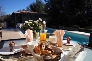 una mesa con desayuno de pan y zumo de naranja en La Maison D'en Haut en Provence, en La Roquebrussanne