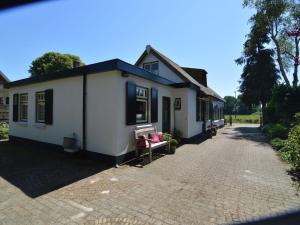 une petite maison blanche sur une route en briques dans l'établissement Holiday home near the Drents Friese Wold, à Nijeberkoop