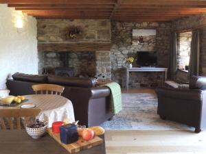 a living room with leather furniture and a stone wall at Stable Cottage in Newport