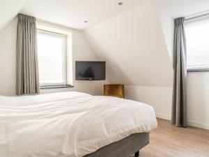 a bedroom with a bed and a tv on the wall at Sunny Bungalow in Heart of Texel in De Cocksdorp