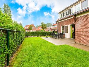 um quintal com um edifício de tijolos e uma cerca em Cozy detached house near Breskens with garden and two nice terraces em Breskens