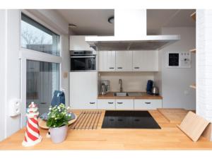 a kitchen with white cabinets and a table with a plant at Quiet location yet close to the beach and center large enclosed garden in Renesse