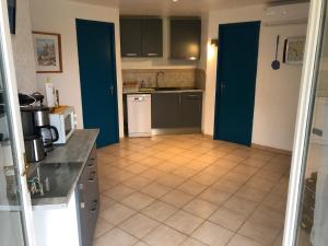 een keuken met blauwe deuren en een tegelvloer bij Chalet La Dragonniere in Vias