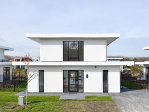a white house with black windows at Luxury villa on the waterfront with jetty in Zeewolde