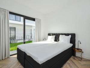 a bedroom with a large bed and a large window at Luxury villa on the waterfront with jetty in Zeewolde