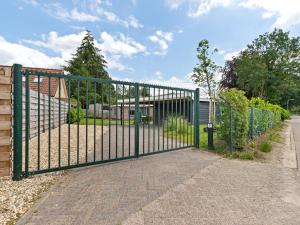 a green metal gate in front of a house at Quaint Holiday Home in Putten with Garden in Putten